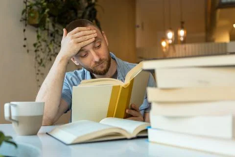 Remote worker reading a book at a cafe while studying for an online course .. Stock Photos