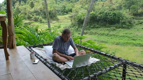 Remote worker sips coffee in hammock with laptop Stock Footage 307079977