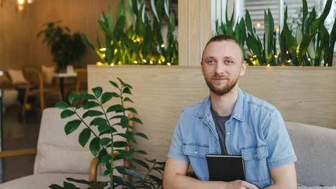 Remote worker sits in modern cafe holding notebook while engaging in online.. Фото