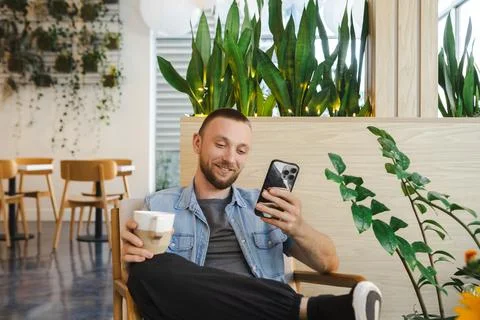 Remote worker uses smartphone while enjoying coffee in a bright workspace d.. Photos