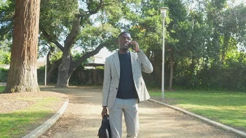 Remote Worker Walks Through Park on Phone Before Setting Up for the Day. Stock Footage 308749739