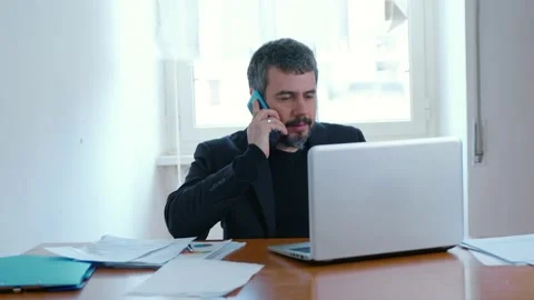Remote working - employee at home in front of the computer talks on phone Stock Footage 149300154