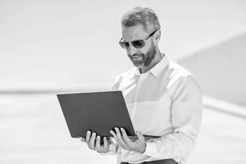 Remote working. Video conference. Businessman working on laptop outdoor. Man has Stock Photos