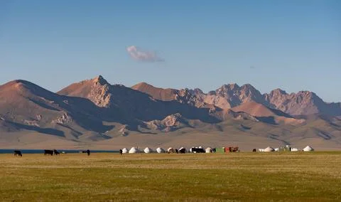 Remote yurt camp beneath dramatic mountain peaks in rural Kyrgyzstan Stock Photos