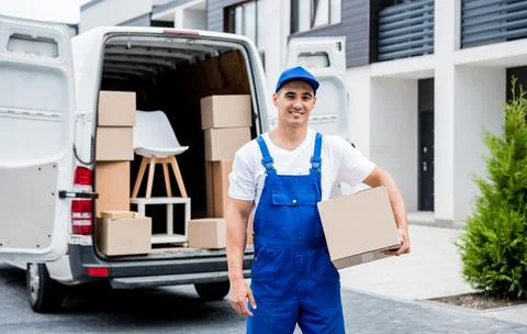 Removal company worker unloading boxes from minibus into customer's home Stock Photos
