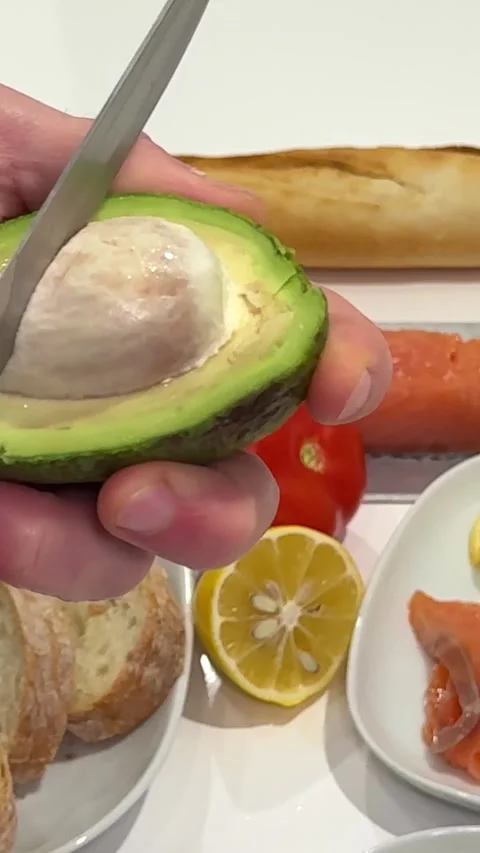 Remove the avocado pit with a knife Man Peeling Ripe Avocado In The Kitchen Stock Footage 327293850