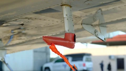 Remove before flight pitot tube cover under the wing of a parked airplane, Stock Footage 289680049
