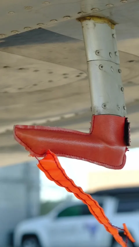 Remove before flight pitot tube cover under the wing of a parked airplane, Stock Footage 306078612