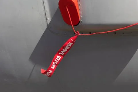 Remove before flight - safety warnign red ribbon and tag. Detail of airplane, Stock Photos
