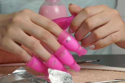 Remove the old gel polish using nail clips. The girl does her own manicure. B Stock Photos