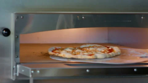 Remove pizza from the industrial oven. Stock Footage 159338937