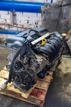 Removed car engine with intake manifold and alternator in auto repair workshop Foto stock