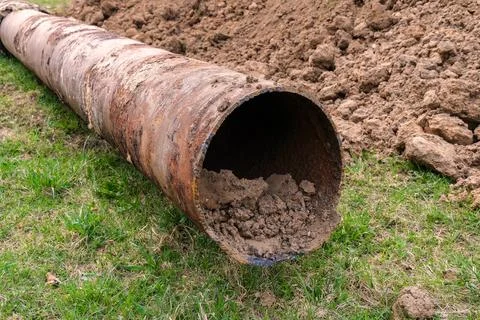 Removed corroded heating pipe lying on grass after excavation Stockfoto's