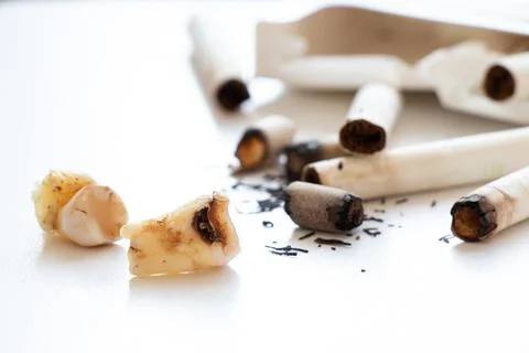 Removed decayed teeth with caries lie next to cigarette butts and tobacco, .. Stock Photos