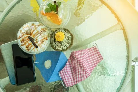 Removed protective two face mask place on the table with iced caramel macchia Stock Photos