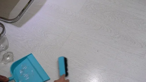 Removes the broken glass from the floor. Sweeps the glass into the scoop 库存影片 76436062