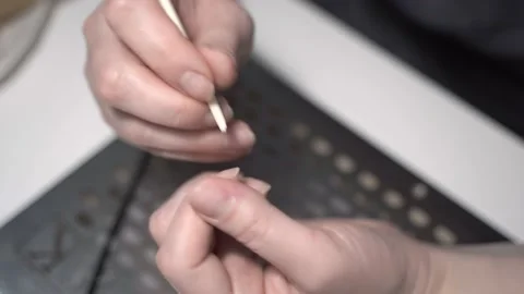 Removes cuticles with a pointed bamboo stick. Gives the a manicure. Video stock 200248962