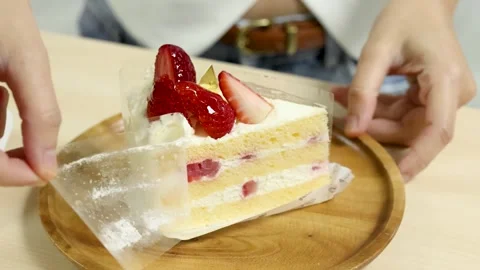 Removing Acetate From Strawberry Cake Slice on Wooden Plate Stock Footage 318343902