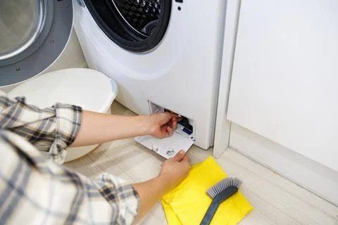 Removing and checking the drain pump filter behind the lower access panel o.. Foto stock