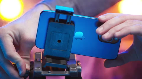 Removing Apple iPhone 15 Pro Max camera from tripod stand 4K Stock Footage 260064682