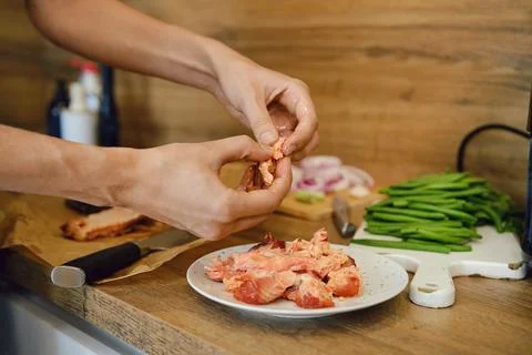 Removing bones from smoked salmon in kitchen with green beans, onion, and k.. Foto stock