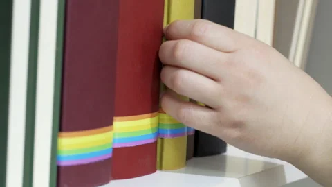 Removing a book with rainbow flag from a shelf in a college Video stock 289724406