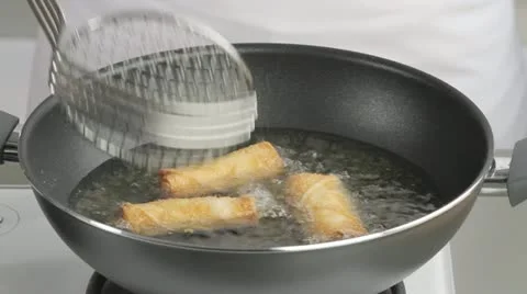 Removing deep-fried spring rolls from the pan Stock Footage 24666616