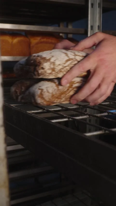 Removing Fresh Rye Bread from Bakery Rack Stock Footage 345878702