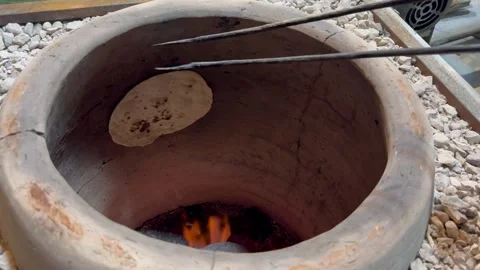 Removing freshly baked flatbread from hot clay tandoor oven, horizontal Stock Footage 345156615