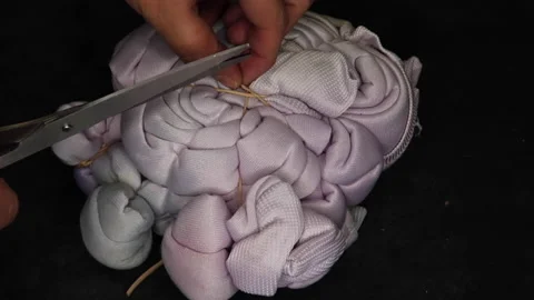 Removing garters with scissors from a tie dye garment Stock Footage 175523939