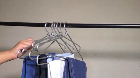 Removing the hangers with clothes from the rod Stock Footage 128199016