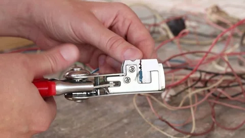 Removing insulation from a blue electrical wire using an automatic stripper Stockbeeldmateriaal 344807919