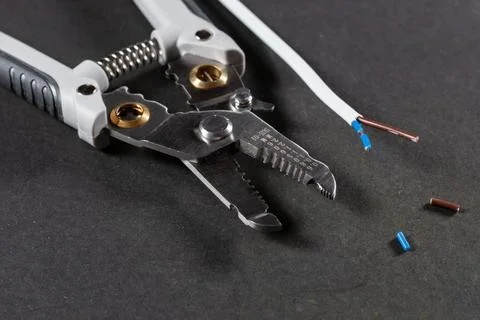 Removing the insulation from the conductor using a tool. Wire stripping tool  Stock Photos