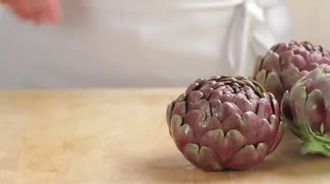 Removing leaf tips from artichokes and sprinkling the cut surface with lemon Stock Footage 24661336
