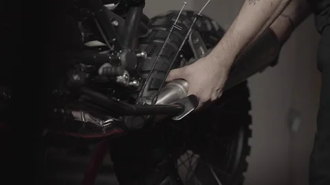Removing a muffler from a motorcycle in a workshop Stock Footage 125446365