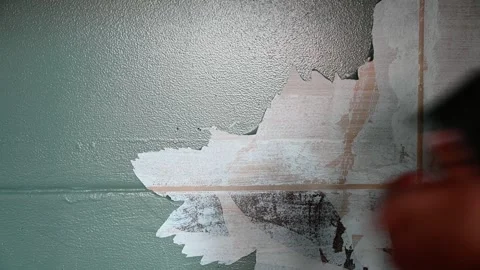 Removing old paint off the wall with scraper after heating it using heat gun Stockbeeldmateriaal 252218550