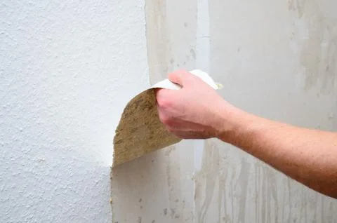 Removing old wallpaper from a wall during home renovation or repair work Stock Photos
