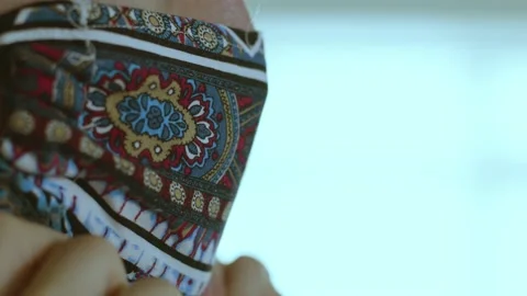 Removing a patterned mask close up on a male face Stock Footage 136354221