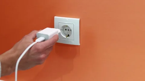 Removing a Phone Charger from Wall Socket Stock Footage 258620755