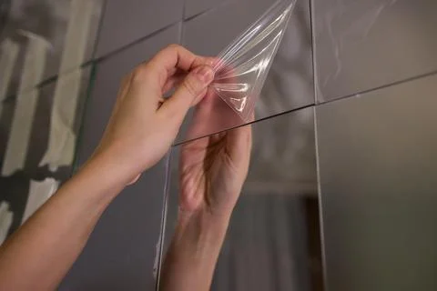 Removing protective layer to reveal clear glass, Carefully removing protective Stock Photos