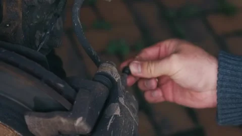 Removing protective rubber bleeder cap from brake caliper during brake system Stock Footage 338389012