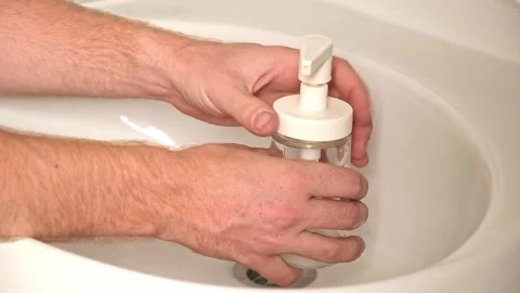 Removing pump to fill container. A man opens glass soap dispenser to pour soap Stock Footage 245657313