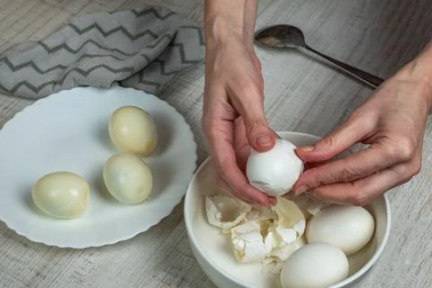 Removing the shell from boiled white eggs. A housewife takes an iron spoon .. Stock Photos