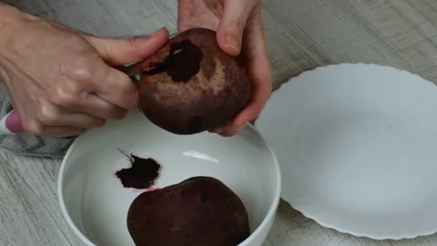 Removing the skin from red boiled beets. A housewife with an iron kitchen knife Stock Footage 233564844