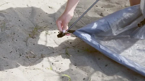 Removing tent pole from loop on sandy ground with sunlit outdoor setting Stock Footage 331200149