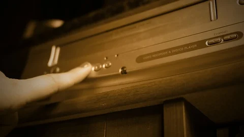 Removing a VHS Tape into VHS player - old retro color graded sepia concept Stock Footage 89987380