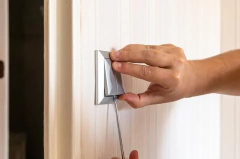 Removing a wall light switch with a screwdriver. Electrical work at home Stock Photos