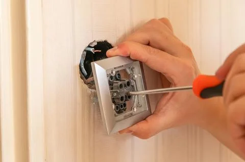 Removing a wall light switch with a screwdriver. Electrical work at home Stock Photos