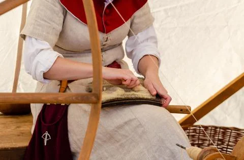 Renaissance woman processing wool on yarn. Medieval spinning wheel. Stock Photos