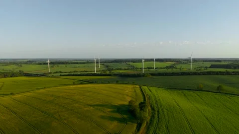 Renewable electricity flowing from wind farm across patchwork rural fields 動画素材 339342848